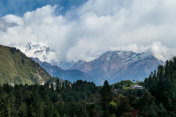 Obraz premium Dziewczyna z dużym niebieskim plecakiem wędruje wzdłuż kamienistej ściany na Annapurna Circuit Trek w Himalajach w Nepalu. Wokół niej są łańcuchy górskie. Strome i jałowe zbocza. Odkrywanie i doświadczanie