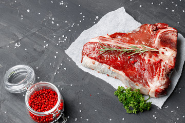 Raw fresh meat t-bone steak with spices on a dark background, close up