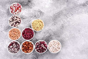 Pulses health food selection in white porcelain dishes over concrete background