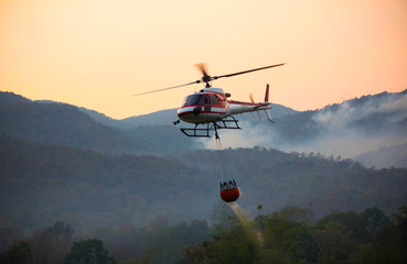 Der Helikopter schöpft Wasser aus dem Stausee und wird bewässert, um den brennenden Wald in den Bergen zu löschen.