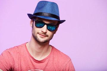 Young hipster man wearing blue hat. Studio shot over pink background.