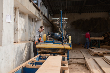 Young man carpenter at the wooden sawmill