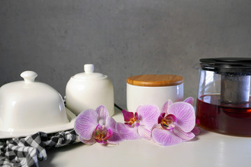  hot black tea in white cup and pink orchids on white table	
