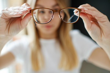The young woman has poor eyesight. Girl holds glasses for sight in her hands. 