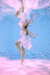 A woman underwater in a pool wrapped in cloth