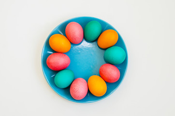 colored easter eggs on a blue plate on a white background