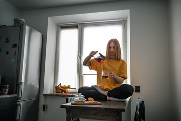 bored girl pours tea sitting on the table in yoga pose
