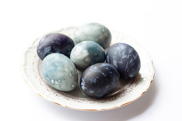 a white plate with Easter eggs painted in dark and light shades of blue on a white background