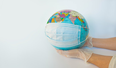 Earth globe dressed in a protective mask on the hands of a man in protective gloves. Symbol that people all over planet are quarantined due to epidemic and pandemic of Coronavirus. White background.