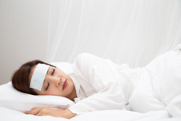 Young Asian woman with high fever while sleeping on white bed at home, Sick symptoms include fever,...