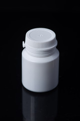 White plastic medical container on white, black background..pill bottle