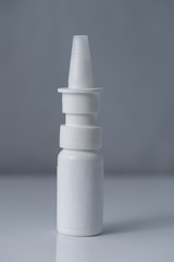 White plastic medical container on white, gray background..nasal spray