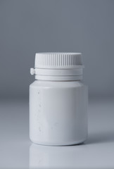 White plastic medical container on white, gray background..pill bottle