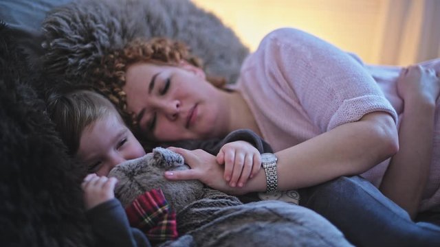 Beautiful young mom with a little cute daughter sleep on the bed in the bedroom