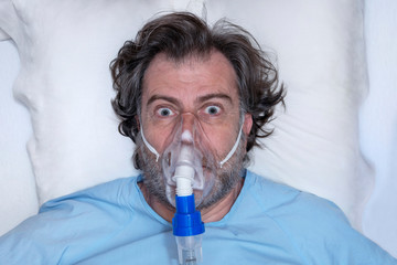 Aerial portrait of an elderly person, with oxygen mask, in a hospital bed