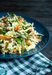 Salad of white cabbage, seaweed, carrots and herbs in a plate close-up. A fresh vegetable salad. Vegetarian dish.