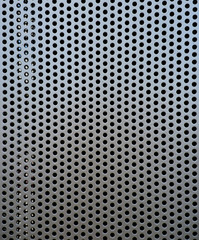 Grey metal plate with many small round holes, a ventilator plate covering an air duct.