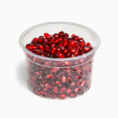 Red juicy pomegranate fruit seeds in in plastic box / package container isolated on white background. Organic Food.