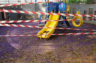 Children playground empty and full of dirty leaves, wrapped in barricade tape, closed due to...