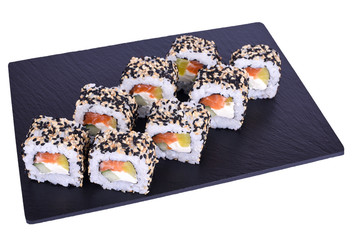 Traditional fresh japanese sushi rolls on a black stone Atami on a white background. Roll ingredients: salmon, philadelphia cheese, daikon radish, cucumber, nori, rice, sesame mix.