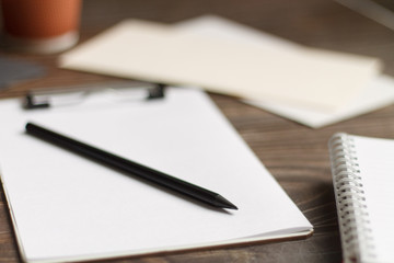 Close-up of a black tablet with a sheet of notepads and glasses with coffee on a wooden table with a blurred background. office Desk concept.