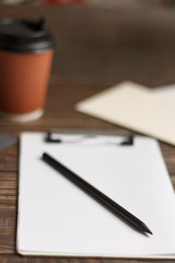 Close-up of a black tablet with a sheet of notepads and glasses with coffee on a wooden table with a blurred background. office Desk concept.