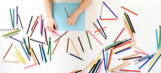 Top view of a boy kid hands who is painting on a blue paper