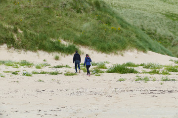 Ein Mann und eine Frau laufen in den Dünen entlang