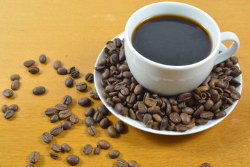 cup of black coffee with beans in white cup on the wooden table