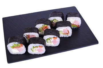 Traditional fresh japanese sushi futomaki on black stone Futomaki Yakito on a white background. Roll ingredients: ham, philadelphia cheese, cucumber, bell pepper, lettuce, nori, rice.