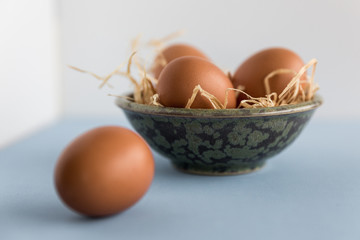 Braune Eier in einer Schale aus Ton im Strohnest