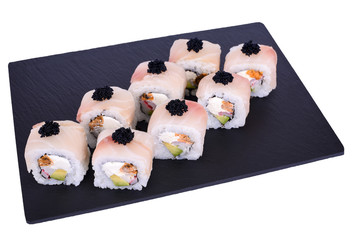 Traditional fresh japanese sushi rolls on a black stone Dragon Izumi on a white background. Roll ingredients: izumai perch, philadelphia cheese, surimi, tomago omelette, avocado, black tobik, nori, ri