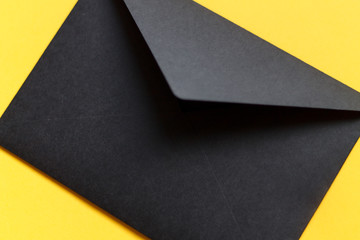 black envelope on a yellow background close up with space for the inscription