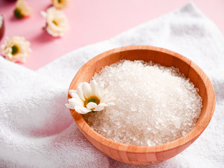 Spa composition. Sea salt, bath towel and flowers on pink background. Close up. Home care concept