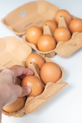 Woman hand choosing brown egg packed in the carton