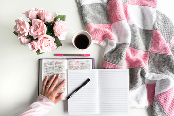 Devotional Bible study. Woman's hand is turning a page of the Bible. With pink roses, black tea and coffee. Background pink, white and grey colors. Baselland, Switzerland - 02.04.2020