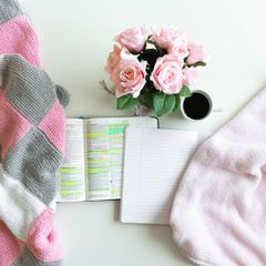 Pink Bible flat lay: Bouquet of pink roses, open Bible, black tea, coffee, journal, notebook, pen and pink blankets. Morning devotional. Rose, white, grey tones. Baselland, Switzerland - 02.04.2020