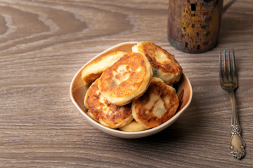 Cheesecakes or Syrniki on a plate on a wooden table. Russian and Ukraine Cuisine