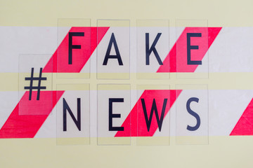 text fake news on yellow background and barrier tape, concept of lie in social media during...