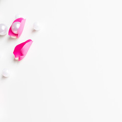 Pink, white, green flat lay: Pearls, pink rose petals, on white bright background. Beautiful set up. Top view, copy space, mock up. 