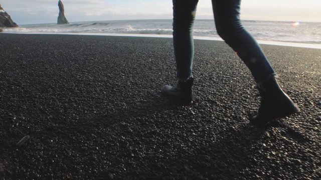Close-up slow motion shot of woman traveler walking on volcanic black sand beach in Iceland. . Reynisfjara Beach