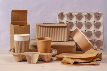 Fototapeta na wymiar Eco craft paper tableware. Paper cups, dishes, bag, fast food containers, box for delivery food and wooden cutlery on wooden background. Recycling concept. Zero waste.