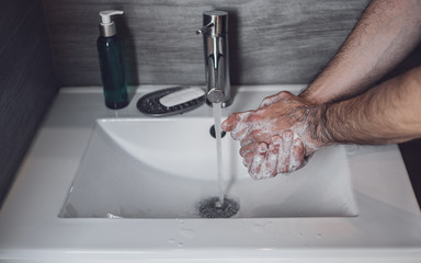 Coronavirus prevention: man washing hands with soap, good hygiene to stop spreading coronavirus.