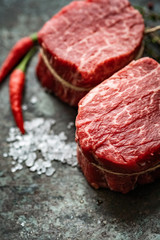 Two juicy filet Mignon beef steaks prepared for grilling with spices and herbs, close up