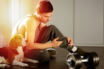 The guy goes in for sports at home with a dog. Exercises for a healthy lifestyle