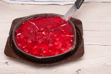 Photo of a bright red open pie stuffed with raspberries in jelly
