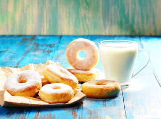 Homemade donuts with a mug of milk on a wooden in a blue background
