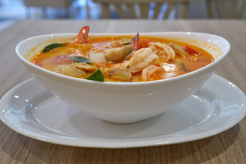 Closeup of a hot Tom Yam Kung soup with shrimps in thai restaurant in Bangkok, Thailand.