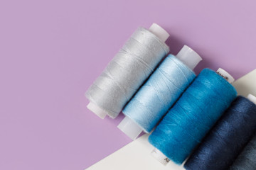 close-up of colored thread for sewing on a lilac background with a place for the inscription. the view from the top