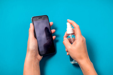 Woman cleaning smartphone with antiseptic. Hygiene concept